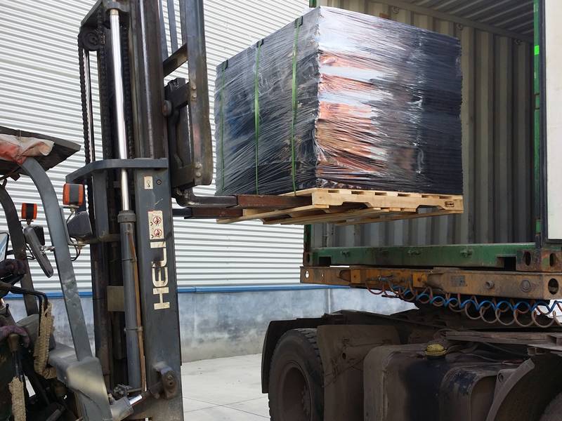 A forklift is carrying laminated bearing pads into container. 