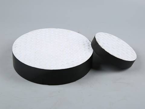 Two different sizes of PTFE round shape laminated bearing pad on gray background.